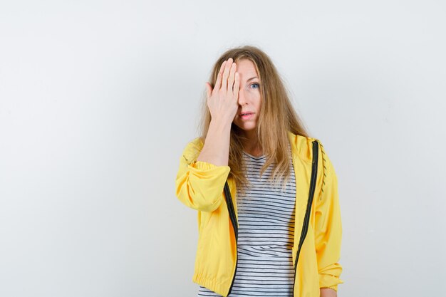 Jonge blonde vrouw in een geel jasje