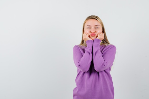 Jonge blonde vrouw in een paarse trui