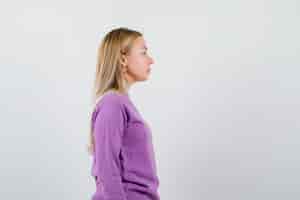 Gratis foto jonge blonde vrouw in een paarse trui