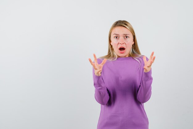 Jonge blonde vrouw in een paarse trui