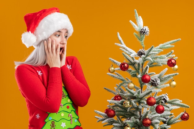 Jonge blonde vrouw in Kerstmissweater en santahoed