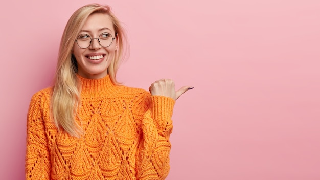 Jonge blonde vrouw in oranje sweater