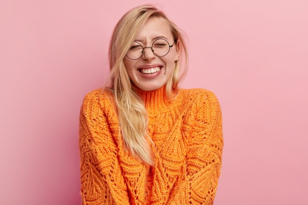 Jonge blonde vrouw in oranje sweater