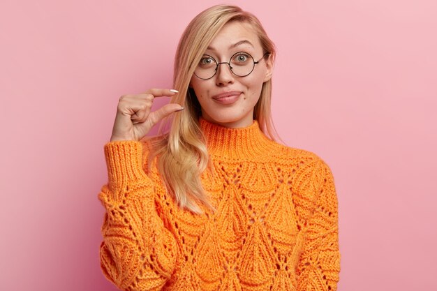 Jonge blonde vrouw in oranje sweater