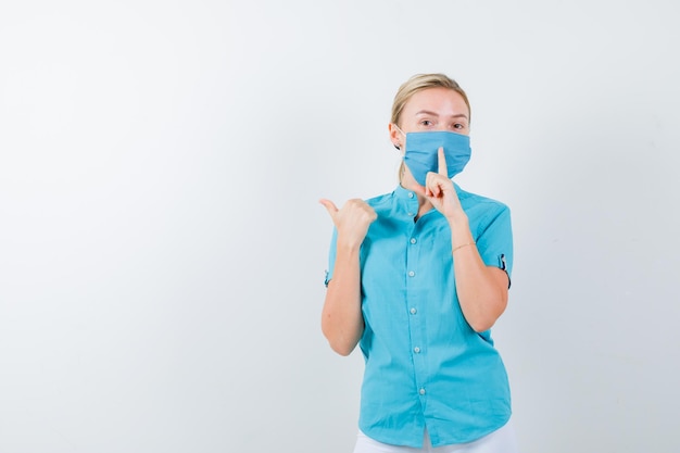 Jonge blonde vrouw in vrijetijdskleding, masker met stilte gebaar geïsoleerd