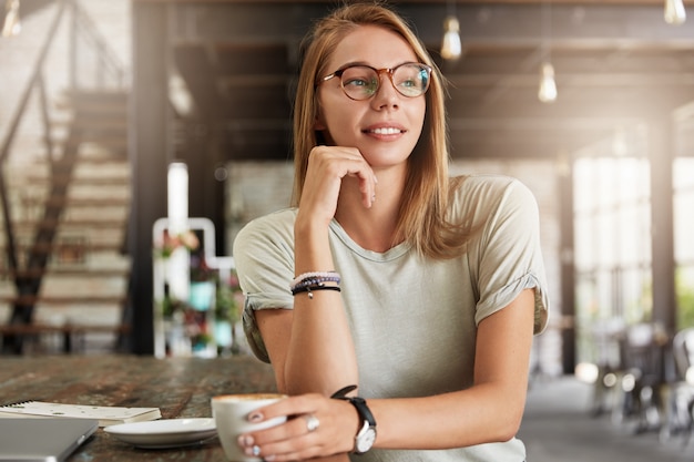 Jonge blonde vrouw met een bril in café