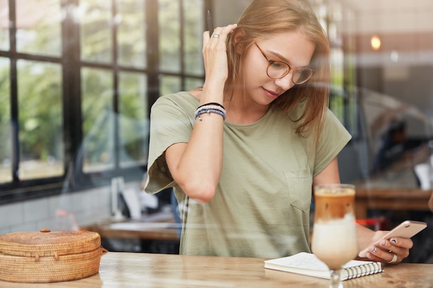 Jonge blonde vrouw met een bril in café