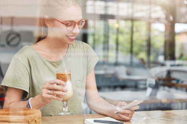 Jonge blonde vrouw met een bril in café