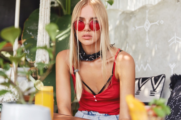 Gratis Foto jonge blonde vrouw met een rode stijlvolle zonnebril, vormt binnen