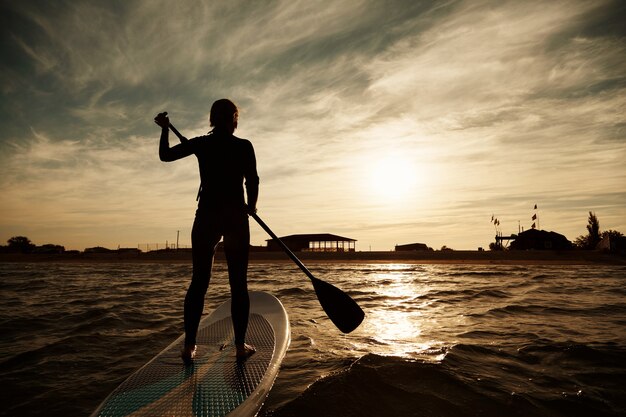 Jonge blonde vrouw op paddleboard op zee