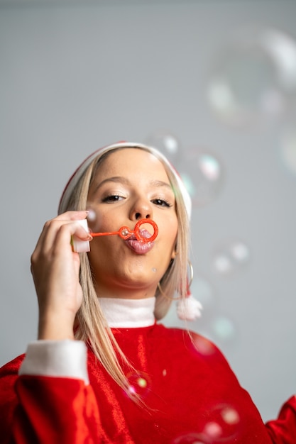 Jonge blonde vrouw poseren in een miss Santa Claus-kostuum en bellen blazen