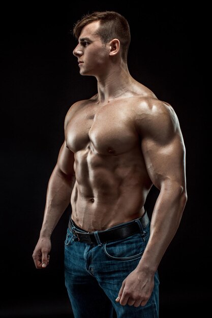 Jonge bodybuilder man op zwarte achtergrond. Mannelijke torso. spierverlichting