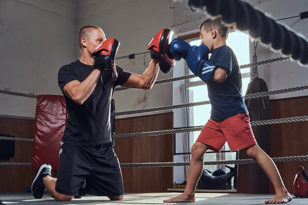 Jonge boksertrainer traint nieuwe kleine jongensbokser voor speciale wedstrijden.