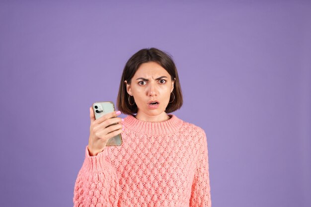 Jonge brunette in roze trui geïsoleerd op paarse muur