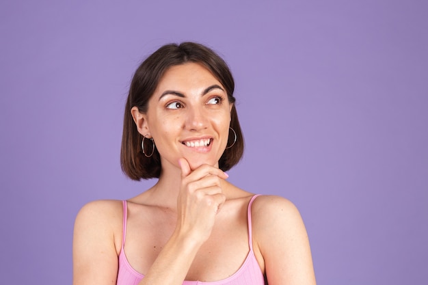 Jonge brunette in top geïsoleerd op paarse muur