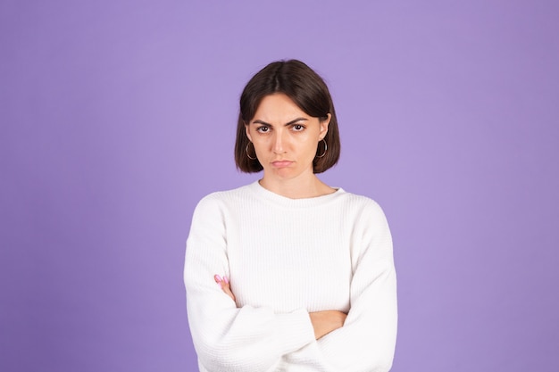 Jonge brunette in witte casual trui geïsoleerd op paarse muur