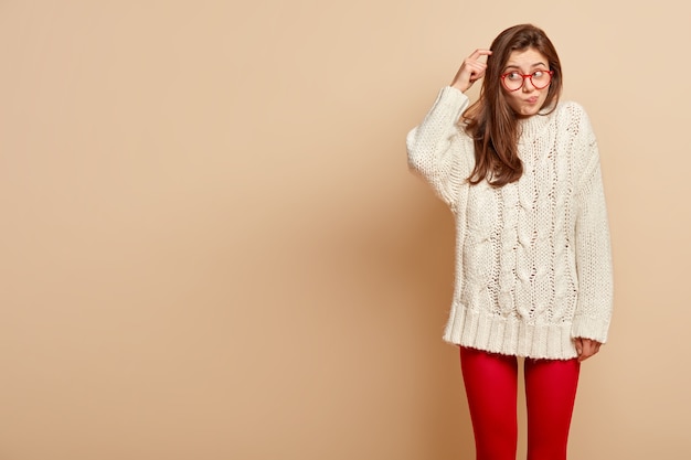 Gratis foto jonge brunette vrouw met rode bril en witte trui