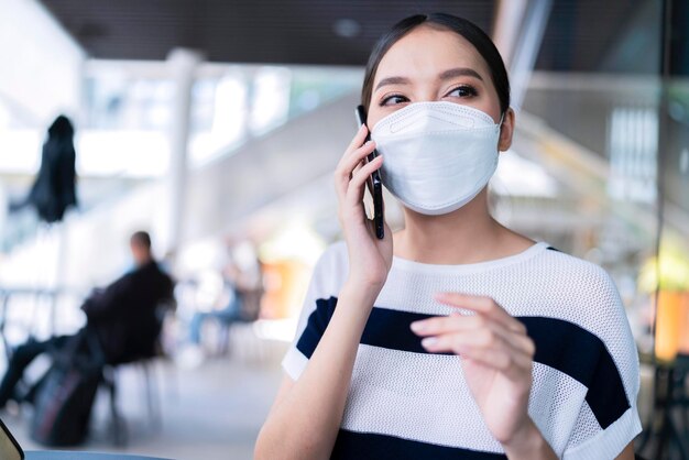 Jonge casual aantrekkelijke vrouw draagt gezichtsmasker handgebaar zegt hallo tegen haar vriend terwijl ze werkt met laptop freelance baan bij café buiten terras winkelgeluk vrouw werkt buitenterras