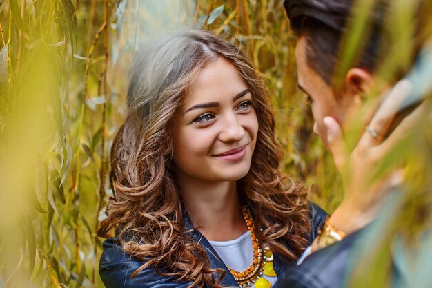 Jonge casual paar genieten van elkaar onder groene boom.