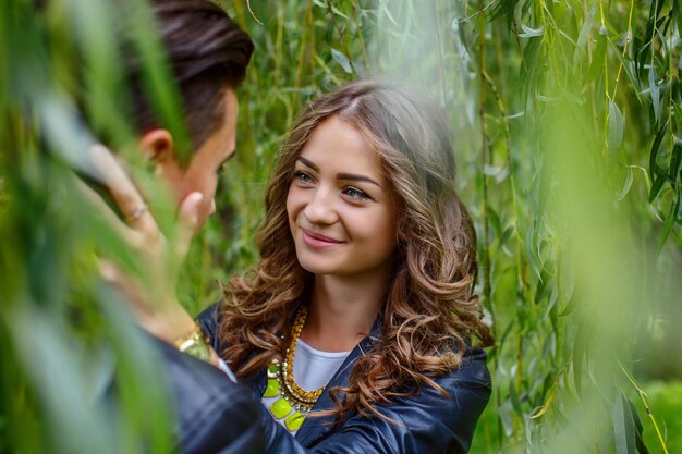 Jonge casual paar genieten van elkaar onder groene boom.