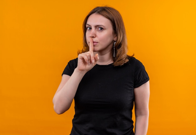 Jonge casual vrouw gebaren stilte op geïsoleerde oranje muur met kopie ruimte