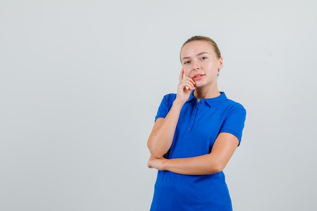 Jonge dame camera in blauw t-shirt kijken en vrolijk kijken