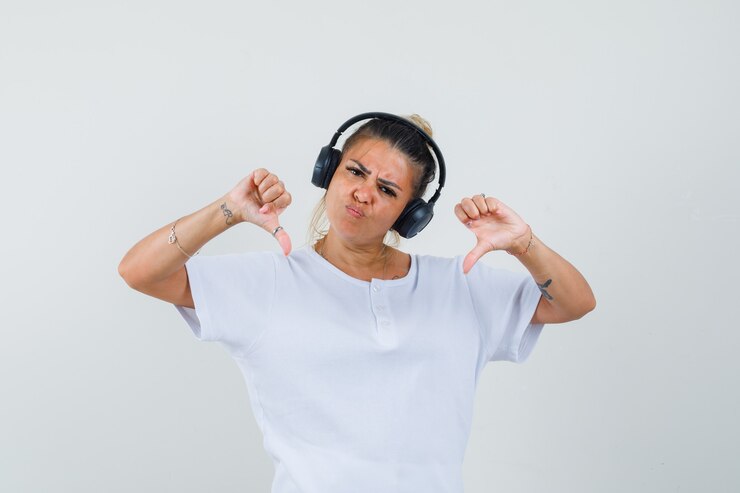 Gratis Foto jonge dame die aan muziek luistert, dubbele duimen neer in t-shirt, vooraanzicht toont.