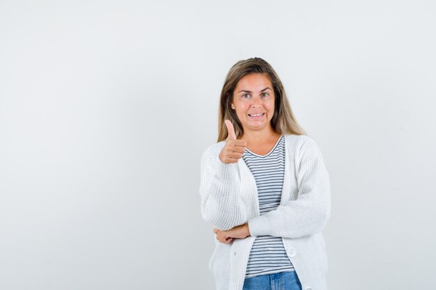 Jonge dame die duim in t-shirt, jasje toont en gelukkig kijkt. vooraanzicht.