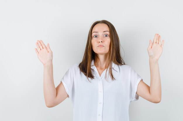 Jonge dame die genoeg gebaar in witte blouse toont en ernstig kijkt.