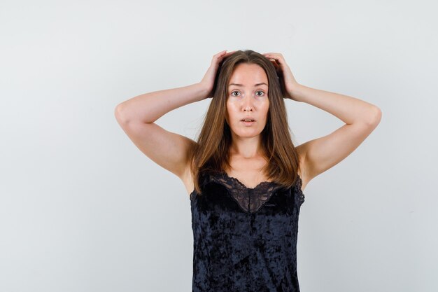 Jonge dame die hand op hoofd in zwarte blouse houdt en onrustig kijkt