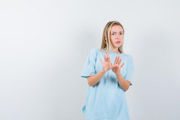 Jonge dame die handpalmen toont in overgavegebaar in t-shirt en er hulpeloos geïsoleerd uitziet