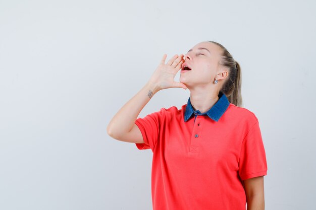 Jonge dame die iets in t-shirt schreeuwt of aankondigt en er ontspannen uitziet