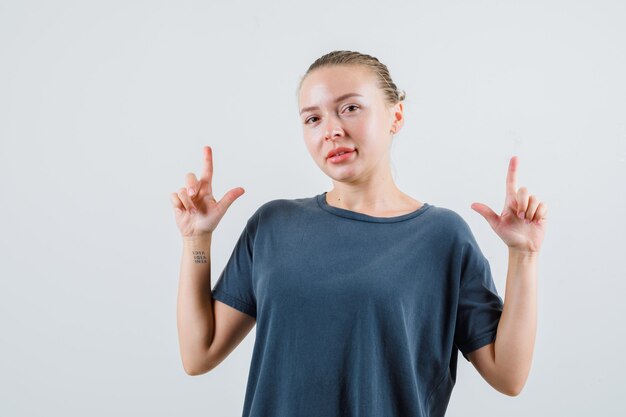 Jonge dame die in grijs t-shirt benadrukt en zelfverzekerd kijkt
