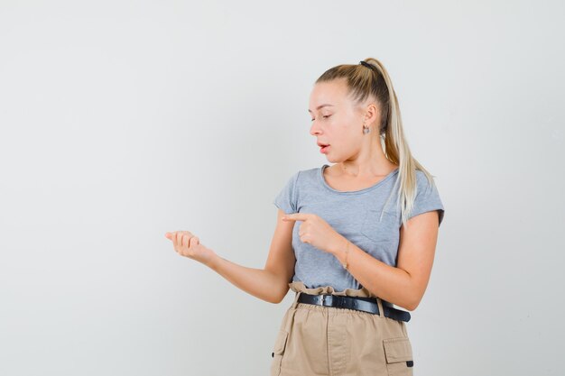 Jonge dame die naar iets wees, deed alsof ze in een t-shirt en broek werd vastgehouden en keek gefocust