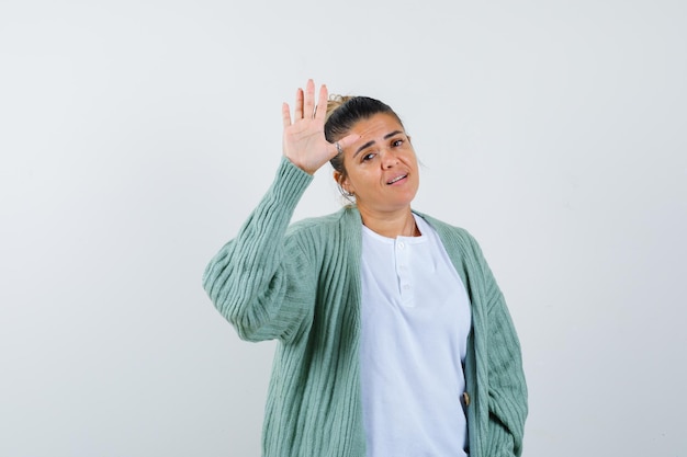 Jonge dame die palm in t-shirt, jas toont en er zelfverzekerd uitziet