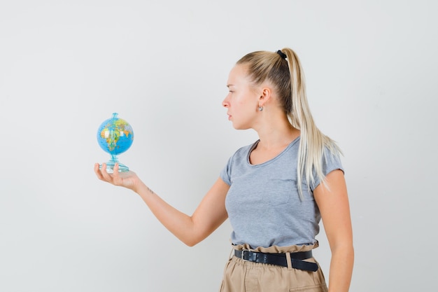 Jonge dame die schoolbol in t-shirt en broek bekijkt