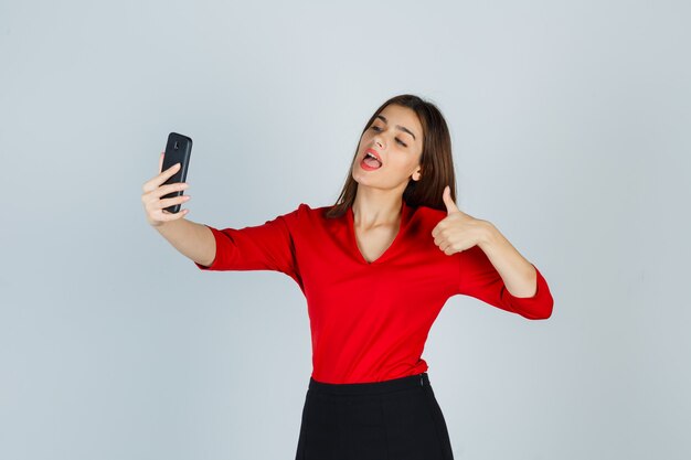 Jonge dame die videogesprek voert terwijl duim in rode blouse wordt getoond