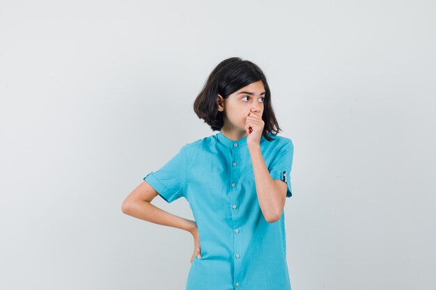 Jonge dame die zich voordeed als iets in een blauw shirt te denken en peinzend te kijken.
