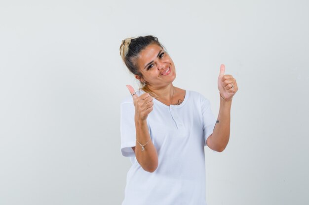 Jonge dame dubbele duimen opdagen in t-shirt en op zoek gelukkig