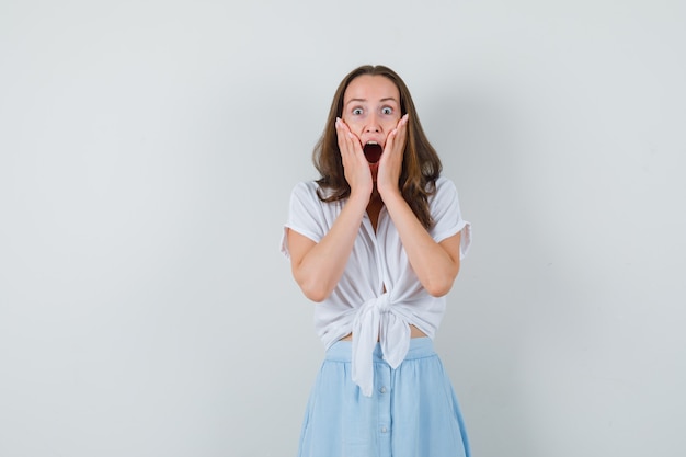 Jonge dame hand in hand op haar gezicht in blouse, rok en op zoek verrast