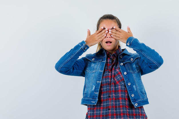 Jonge dame hand in hand op ogen in shirt, jasje en opgewonden kijken. vooraanzicht.