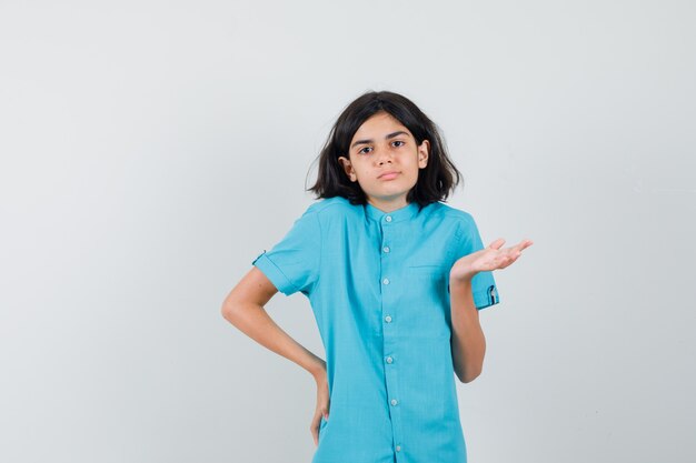 Jonge dame hulpeloos gebaar in blauw shirt tonen en hopeloos op zoek.