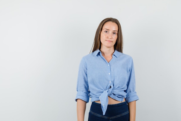 Jonge dame in blauw shirt, broek camera kijken en verstandig kijken