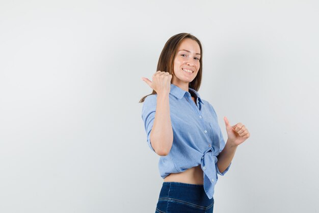 Jonge dame in blauw shirt, broek wijst weg en kijkt optimistisch