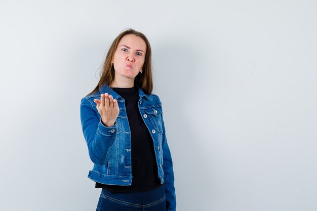 Jonge dame in blouse die de hand op een vragende manier uitrekt en er nerveus uitziet, vooraanzicht.