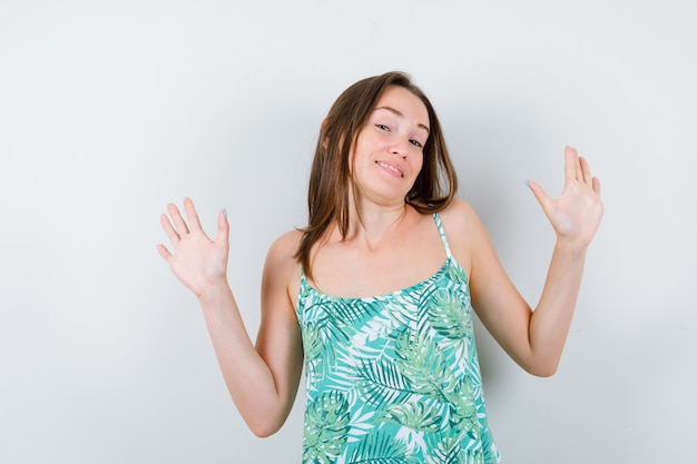 Jonge dame in blouse die handpalmen toont in overgavegebaar en er schattig uitziet, vooraanzicht.