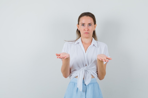 Jonge dame in blouse en rok die handen uitrekt en verbaasd kijkt