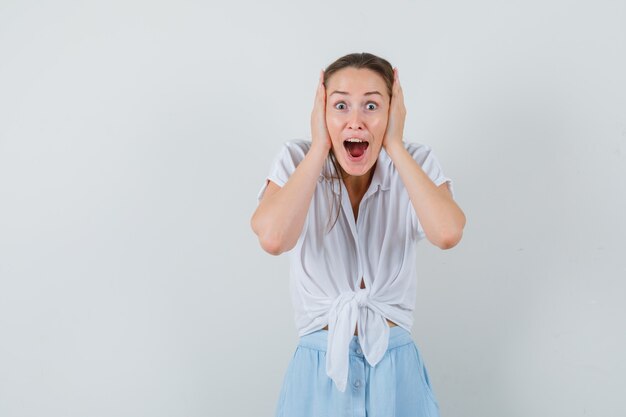 Jonge dame in blouse en rok hand in hand aan het hoofd en op zoek zalig