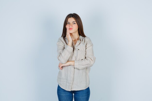 Jonge dame in casual, jeans die lijdt aan kiespijn en er onwel uitziet, vooraanzicht.