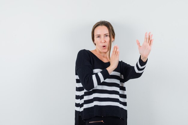 Jonge dame in casual shirt karate hakken gebaar tonen en op zoek zelfverzekerd